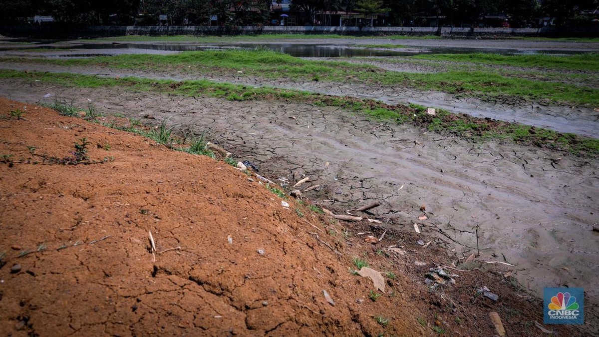 Foto: Seorang warga berjalan di tanah yang retak akibat kekeringan di Danau Cinere, Depok, Jawa Barat, Rabu (27/9/2023). (CNBC Indonesia/Faisal Rahman)