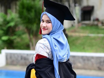 Menghadap kamera dengan senyum semringah, Uty Bonita tampil memesona mengenakan jubah wisuda bernuansa hitam-merah marun dengan kerah kuning dari Universitas Terbuka. Perpaduan hijab segi empat berwarna biru muda membuat wajahnya terlihat semakin cerah dan fresh di hari bahagianya. (Foto: dok Instagram utybonita)