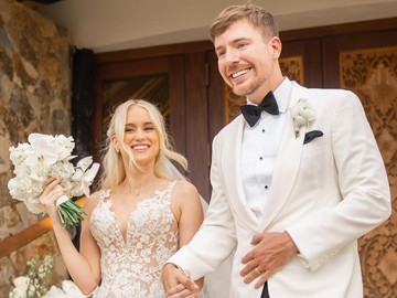 Di momen pernikahan MrBeast tampak gagah mengenakan tuksedo bernuansa putih-hitam, sementara Thea tampil memukau dengan gaun pengantin beraksen renda yang elegan. Keduanya berpose mesra dengan latar pemandangan tropis yang indah. (Foto: dok Instagram mrbeast)