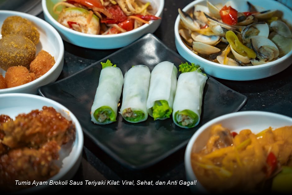 Tumis Ayam Brokoli Saus Teriyaki yang mengkilap dan kaya warna, disajikan dalam mangkuk putih dengan taburan biji wijen di atas nasi putih.