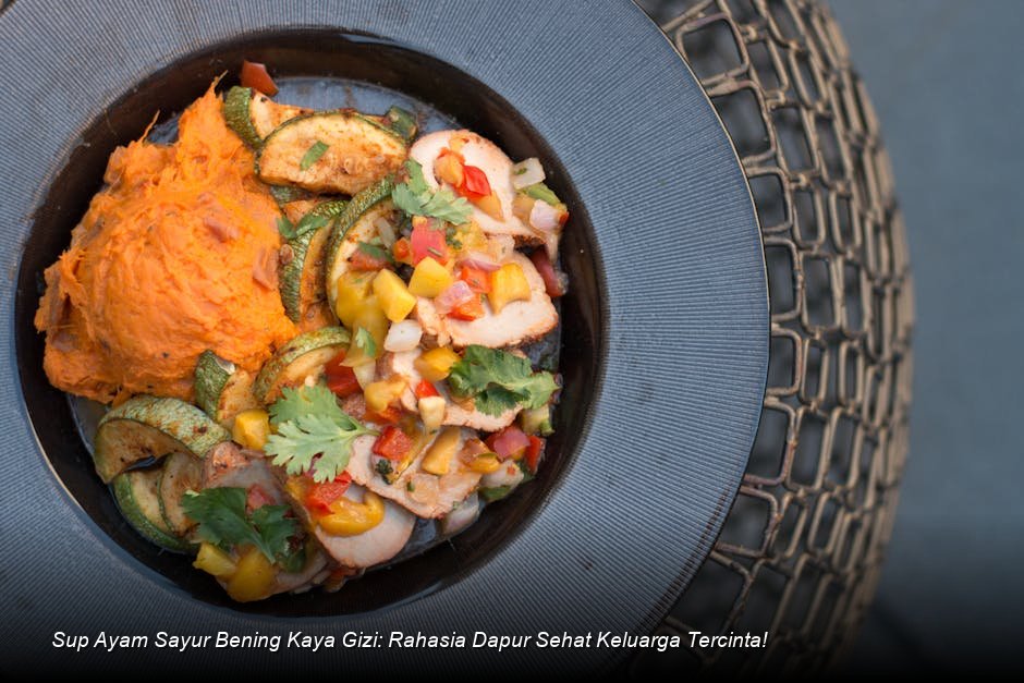Semangkuk besar Sup Ayam Sayur Bening yang mengepul hangat, dengan irisan wortel, kentang, dan taburan daun bawang segar di atasnya.