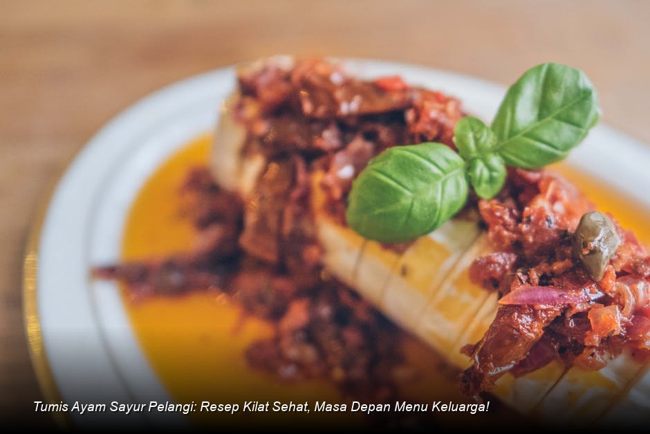 Tumisan Ayam Sayur Pelangi yang menggiurkan tersaji di piring putih, menampilkan potongan ayam, wortel oranye, dan brokoli hijau cerah, dengan taburan biji wijen sebagai garnish.