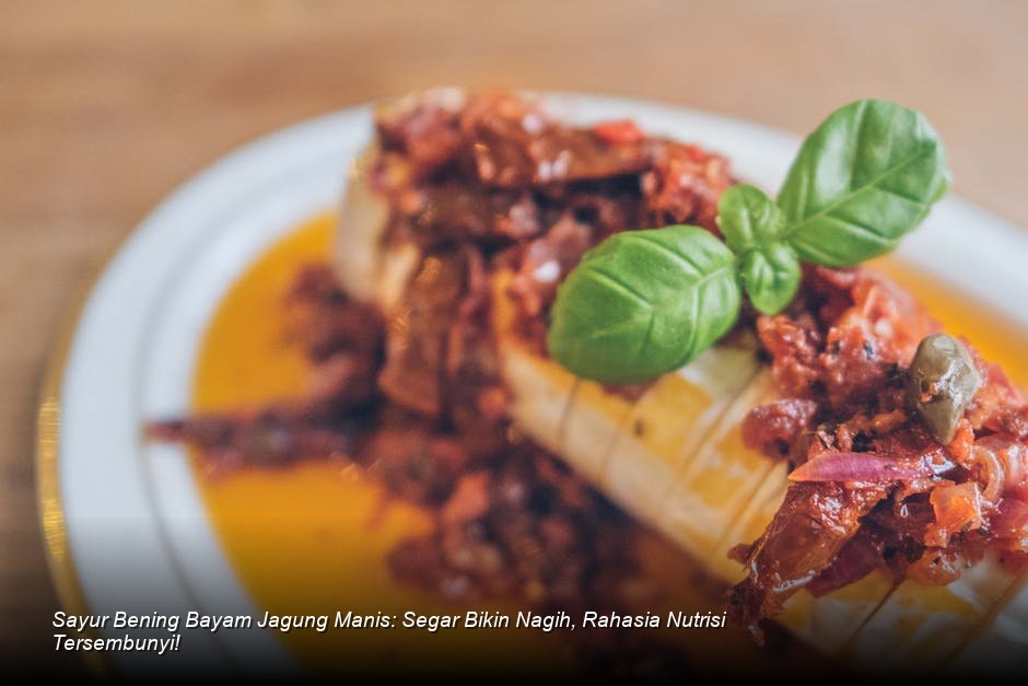 Semangkuk penuh Sayur Bening Bayam Jagung yang masih mengepul, dengan warna hijau cerah dan biji jagung kuning mencolok, disajikan bersama irisan tomat segar sebagai garnish.